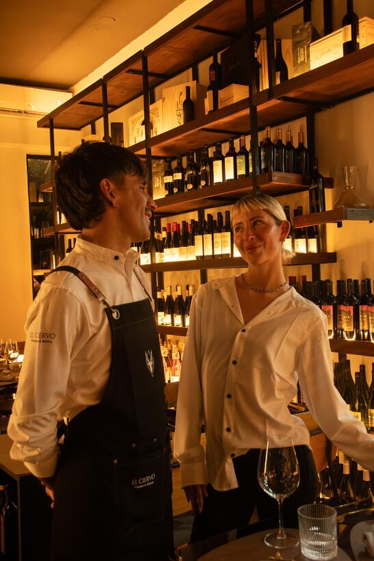 Dos integrantes del equipo frente a los estantes de vinos iluminados